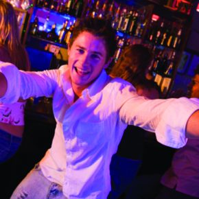 Young man in nightclub approaching camera with arms outstretched